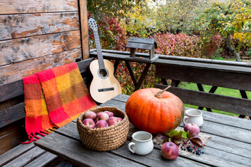 autumn composition with pumpkin and apples and a guitar on an open terrace.  cozy place
