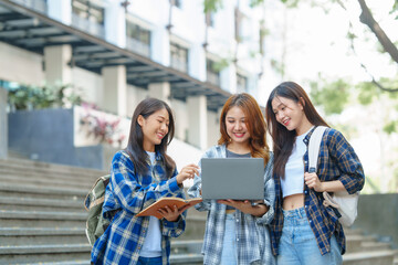 Attractive asian college student using laptop and tablet studying with group of friends together with english language classroom, social media and education concept.