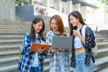 Attractive asian college student using laptop and tablet studying with group of friends together with english language classroom, social media and education concept.