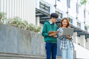 Attractive asian college student using laptop and tablet studying with group of friends together with english language classroom, social media and education concept.