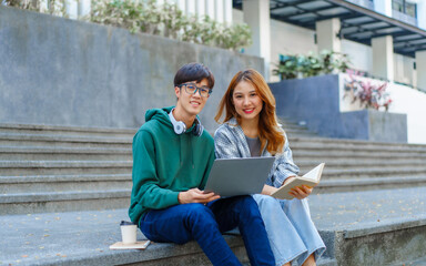 Attractive asian college student using laptop and tablet studying with group of friends together with english language classroom, social media and education concept.