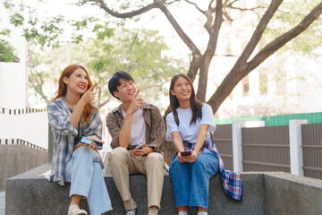 Attractive asian college student using laptop and tablet studying with group of friends together with english language classroom, social media and education concept.