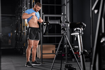 Fototapeta premium Man showing his abs on camera at gym. Online fitness trainer