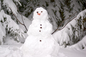Snowman surrounded by evergreen bows covered with snow.