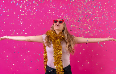 Caucasian girl partying at the disco laughing throwing confetti, isolated on a pink background