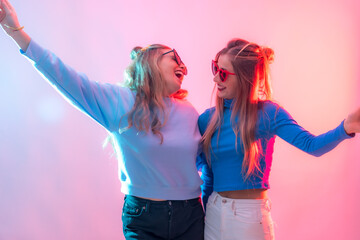 Two young blonde caucasian women dancing in disco, smiling at party