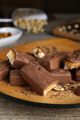 Tasty chocolate bars with caramel and nuts on wooden table, closeup