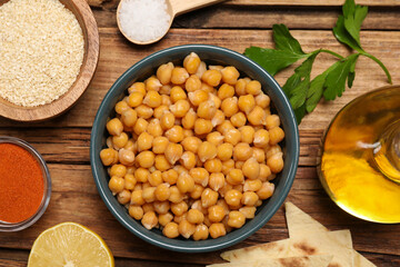 Delicious chickpeas and different ingredients on wooden table, flat lay. Cooking hummus