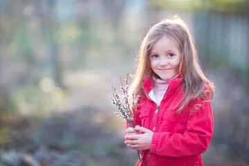 a little girl with a bouquet of willow is looking at the camera and smiling