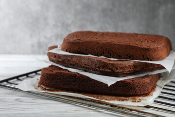 Layers of homemade chocolate sponge cake on white wooden table