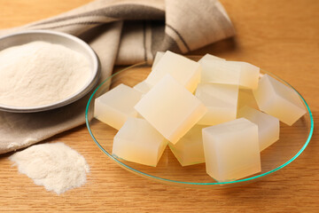 Agar-agar jelly cubes and powder on wooden table, closeup