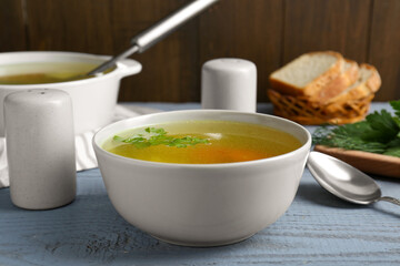 Delicious chicken bouillon with parsley on grey wooden table
