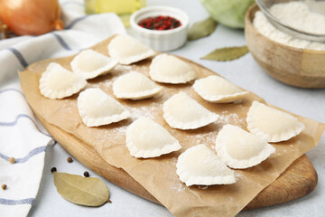 Fototapeta na wymiar Raw dumplings (varenyky) with tasty filling and ingredients on light grey table