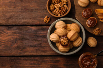 Fototapeta na wymiar Delicious nut shaped cookies with boiled condensed milk on wooden table, flat lay. Space for text