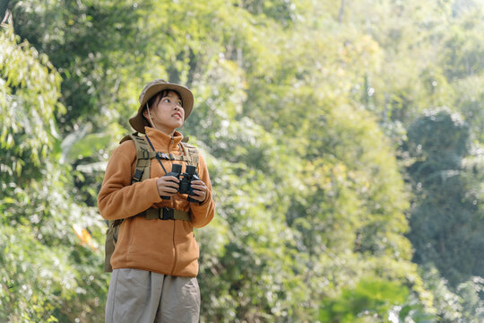 Attractive young girl traveler look around and explore while walk in nature wood with happiness and fun during holiday vacation trip.