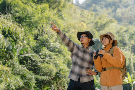 Asian young girl with brother using binoculars in the forest. Explorers and adventurers use binoculars.