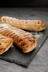 Fresh tasty puff pastry with sugar powder on grey table, closeup