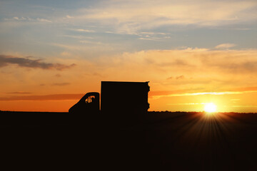 Fototapeta premium Truck driver in vehicle on highway at sunset