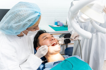 Caucasian dentist examine tooth for young man patient at dental clinic.