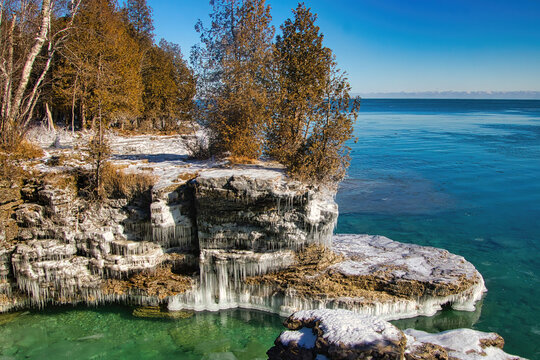 Under a blue sky on a Winter day, the rocky Lake Michigan shoreline is coated in ice at Cave Point, near Sturgeon Bay in Door Comity.