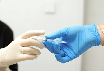 Close up of dental assistant passing syringe to dentist during patient's dental procedure Doctor passing syringe with anesthesia during operation washing gloves close-up people