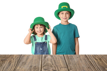 Cute children in leprechaun's hats near table on white background. St. Patrick's Day celebration