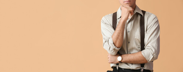 Fashionable gentleman with suspenders on beige background with space for text - obrazy, fototapety, plakaty