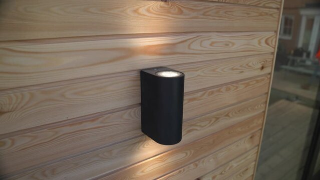 Up and down spot light casting luxury lighting across wooden cladded outbuilding