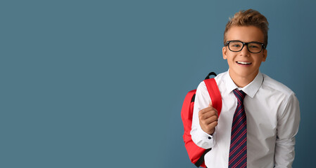 Happy teenage boy with backpack on grey background with space for text