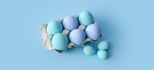 Box with beautiful Easter eggs on light blue background