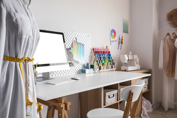 Tailor's workplace with computer and threads in modern atelier