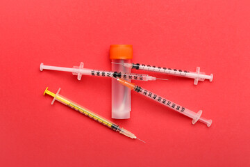 Medical syringes with bottle on red background