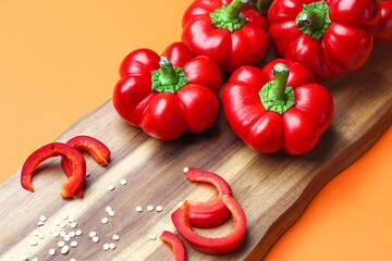 Wooden board of fresh bell peppers on color background, closeup