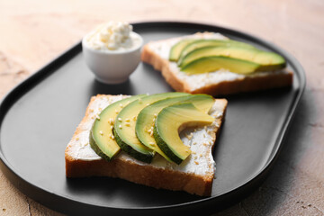 Plate of tasty sandwiches with cream cheese and avocado on color background, closeup