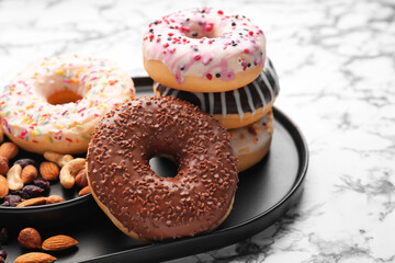 Plate with tasty donuts and nuts on light background, closeup