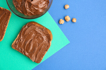 Delicious toast with hazelnut butter on color background