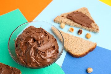 Bowl of tasty hazelnut butter on color background