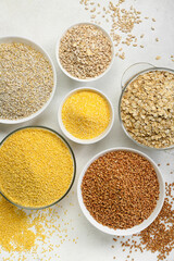 Bowls of different cereals on light background