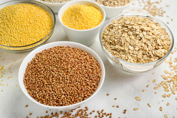 Bowls of different cereals on light background, closeup