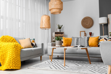 Beautiful interior of living room with cozy grey sofas, table and lamps