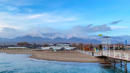 Fototapeta na wymiar View of the mountains and the pier. Beautiful view of the amazing mountain lake. The pearl of Kyrgyzstan is Lake Issyk-Kul. Calm calming natural background.