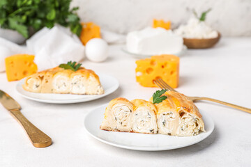 Plates with pieces of delicious cheese pie and parsley leaf on white table