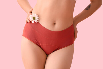 Young woman in menstrual panties with daisy flower on pink background, closeup