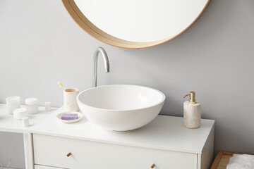 Ceramic sink and bath accessories on drawers in bathroom
