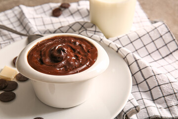 Plate with bowl of delicious pudding, milk and chocolate chips on napkin, closeup