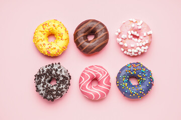 Assortment of delicious donuts on pink background