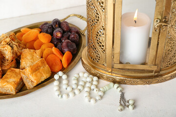 Lantern with treats and prayer beads on white background, closeup. Islamic New Year celebration