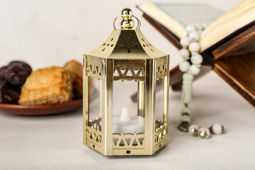 Lantern with Koran and treats on white background, closeup. Islamic New Year celebration