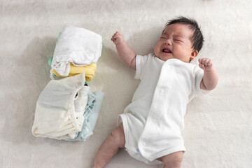 起きている赤ちゃんと畳んだ子供服（0歳2か月、日本人、男の子）