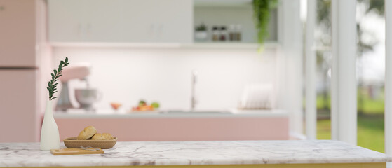 Copy space on white marble kitchen tabletop over blurred background of beautiful pink kitchen.